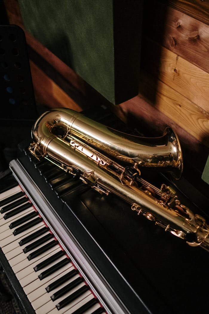 services-01 A gold saxophone resting on a black piano in a cozy, wooden music studio.